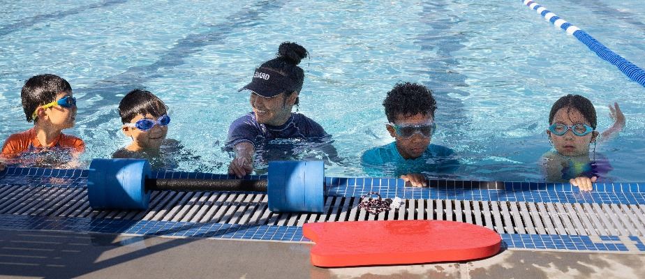 Children at the edge of a pool during a swim lesson