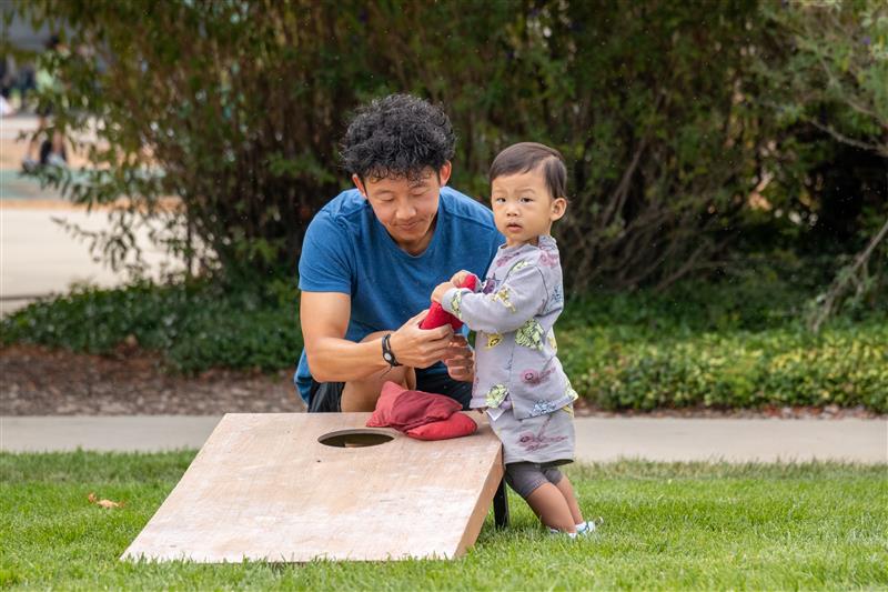 Staff member and participant playing corn hole